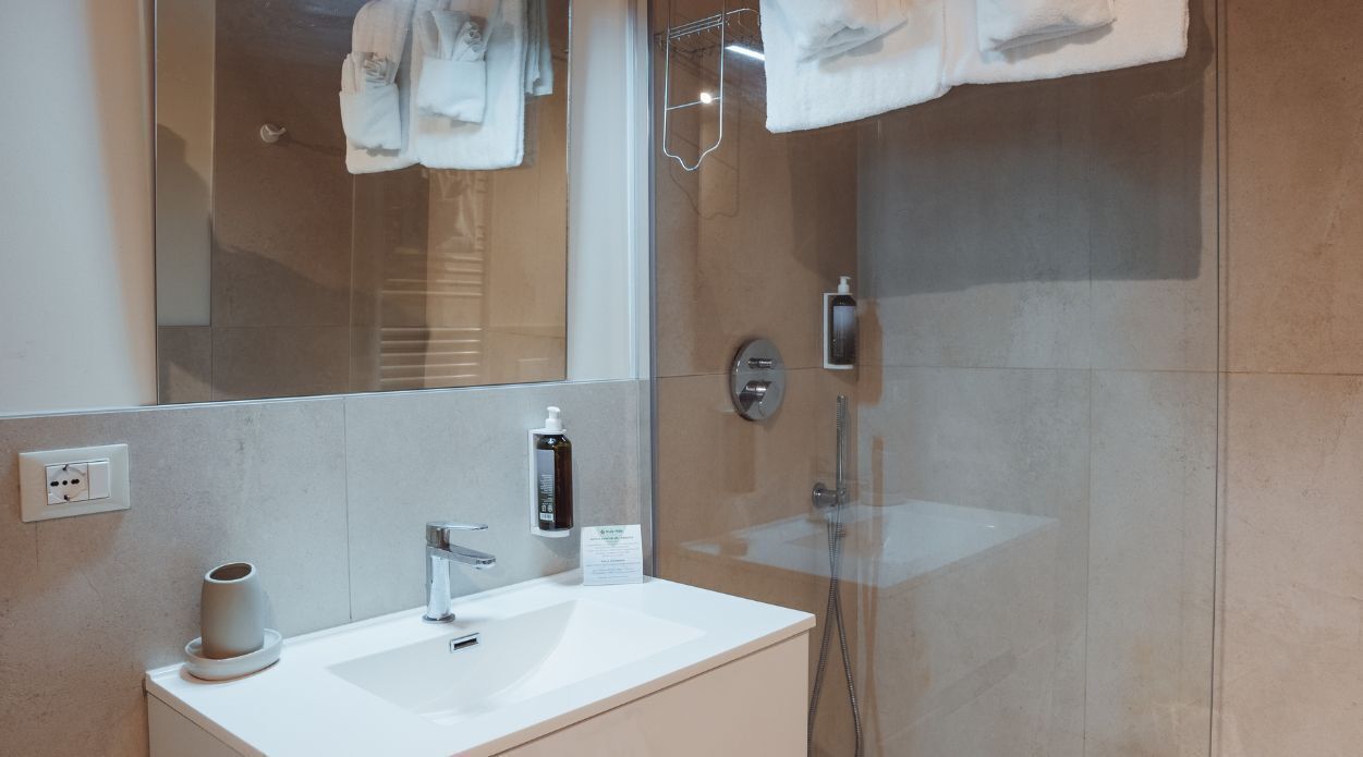 A modern bathroom with a glass shower enclosure, a white sink, and a large mirror.