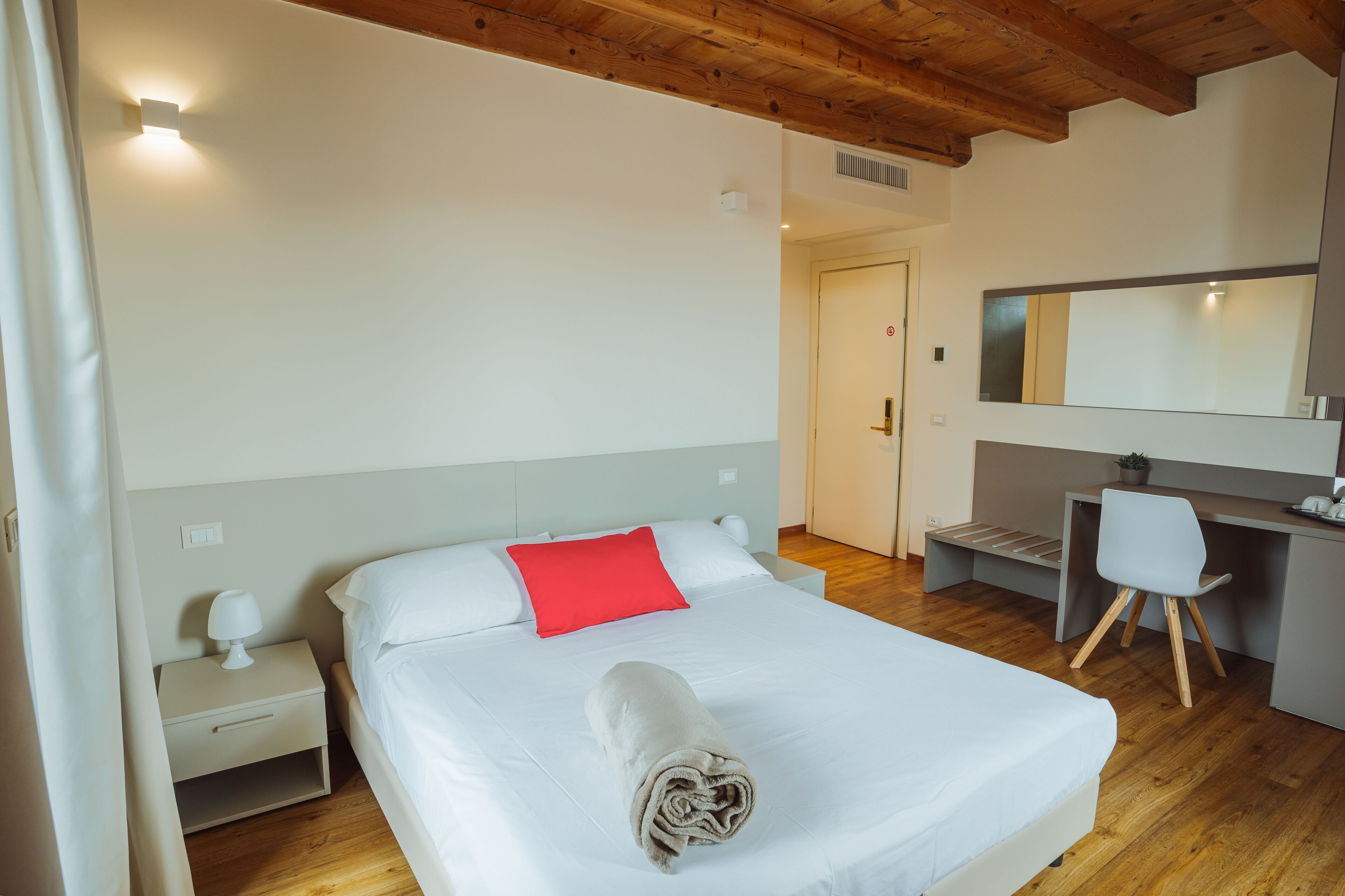 Ein Hotelzimmer mit Bett, Schreibtisch, Stuhl, Nachttisch und Spiegel.
