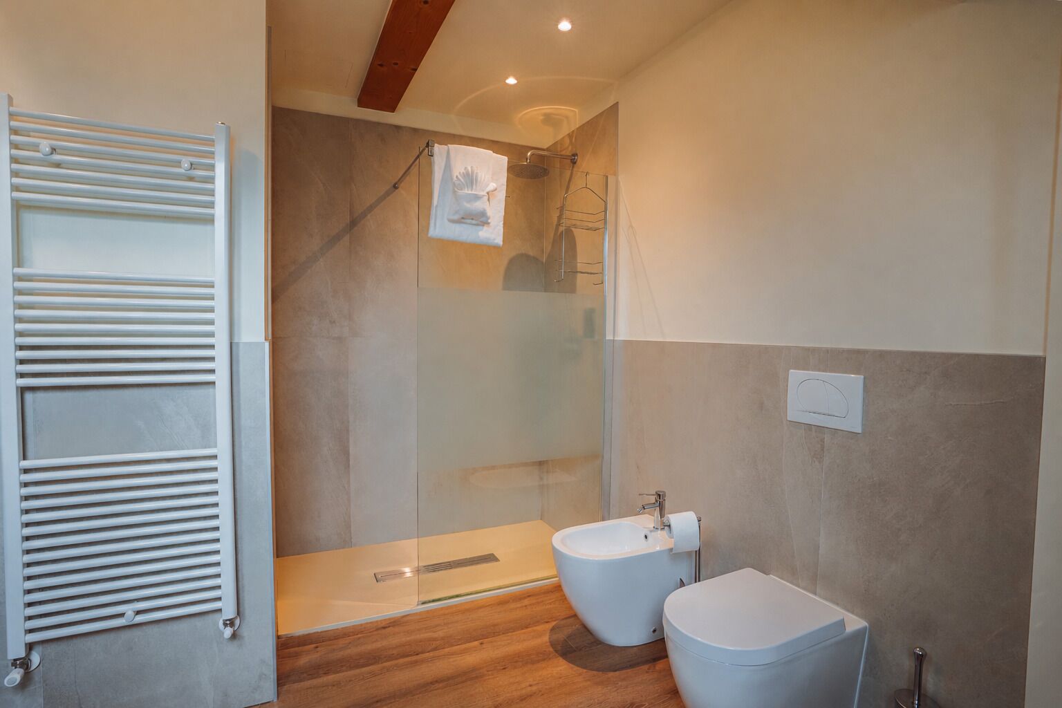 A modern bathroom with a glass shower enclosure, a white toilet, and a bidet.