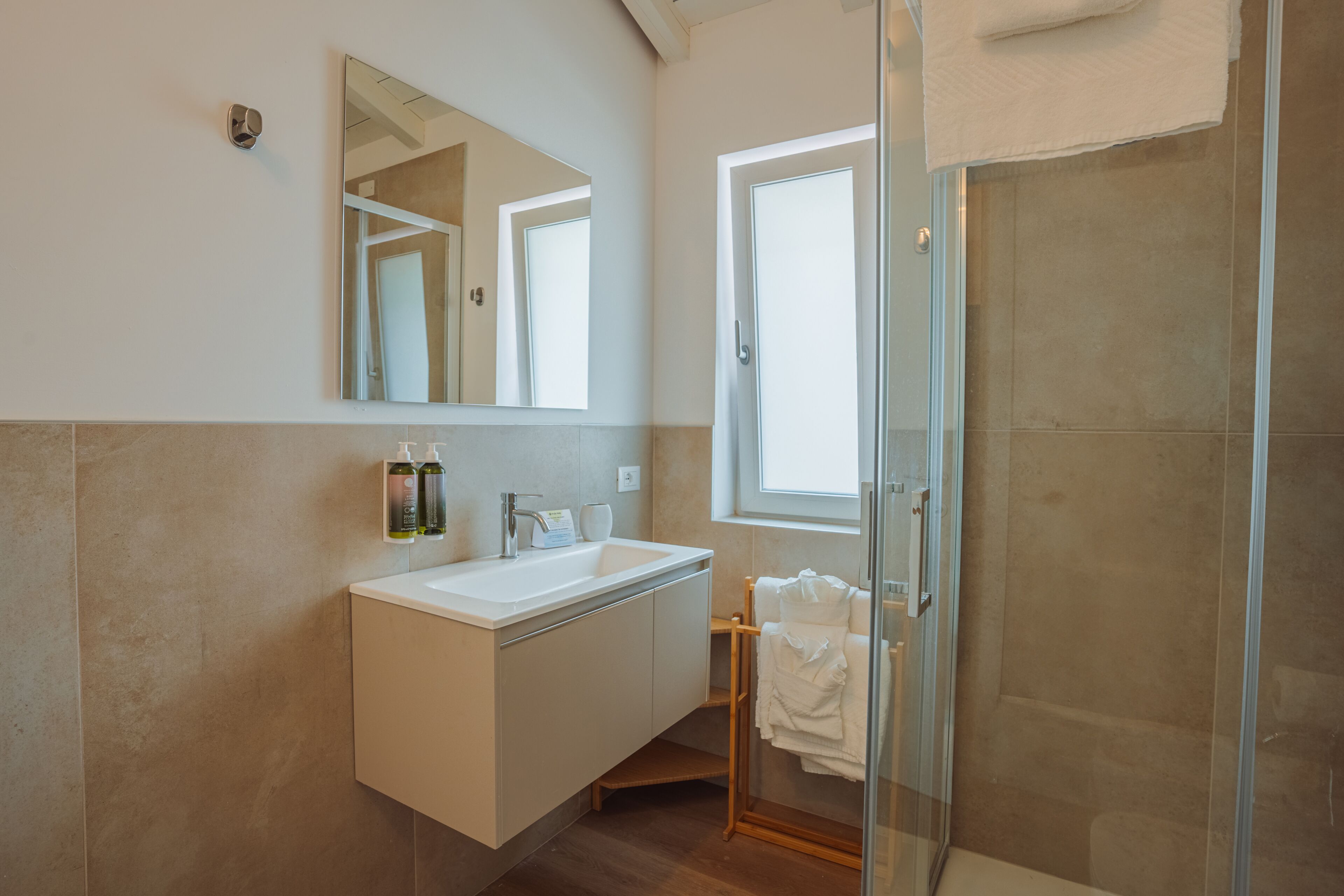 Un bagno moderno con box doccia in vetro, lavandino bianco e specchio sopra.