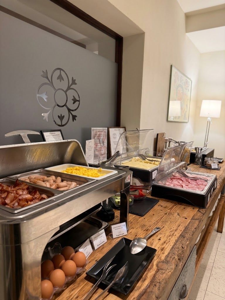 A buffet setup with various food options including eggs, bacon, and different meats.