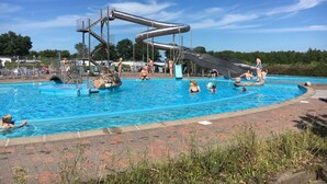 A swimming pool with a water slide and a small island with rocks. - Dancamps Trelde Næs (Fredericia)