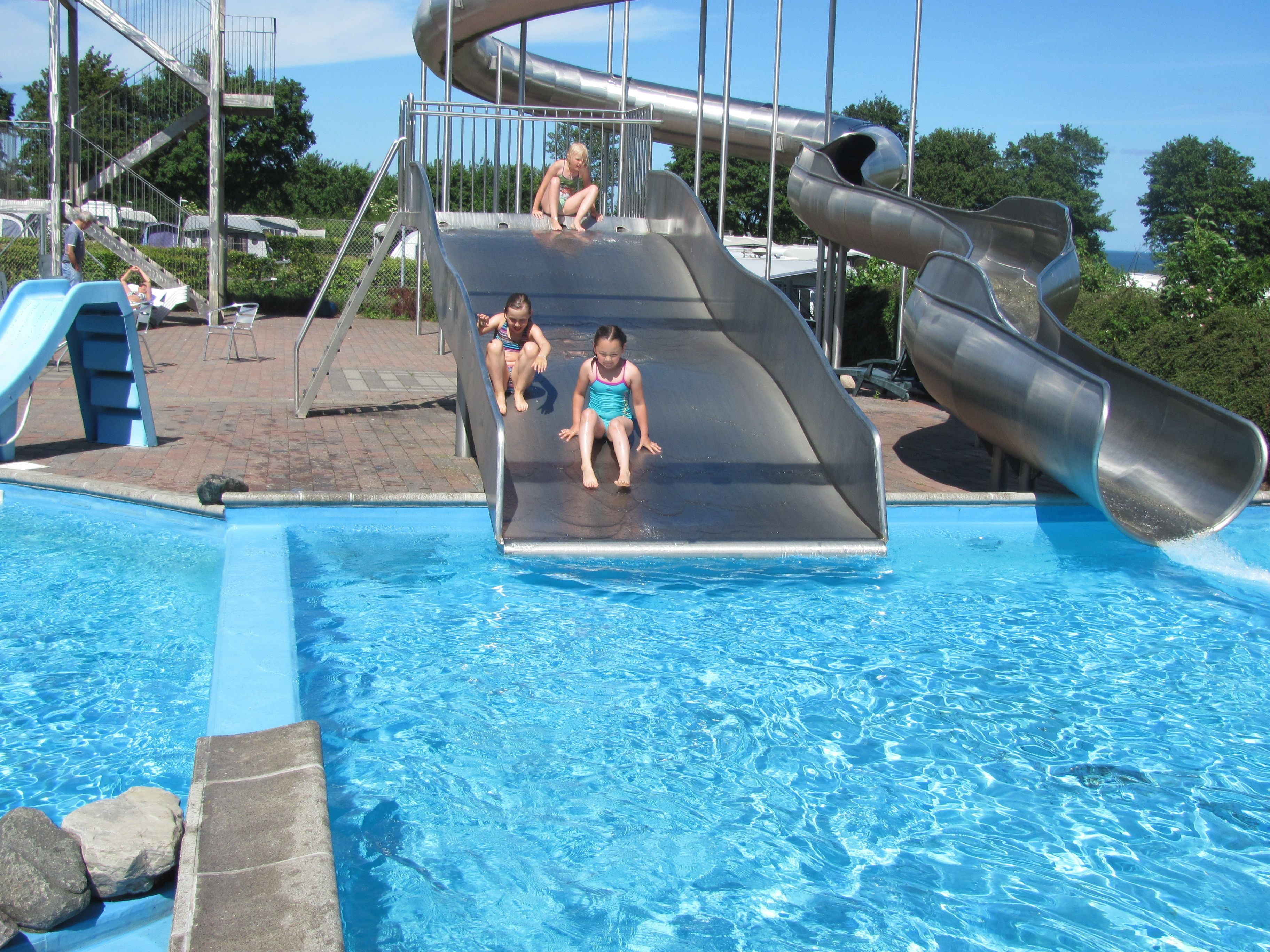 Una piscina con tobogán y una estructura metálica.