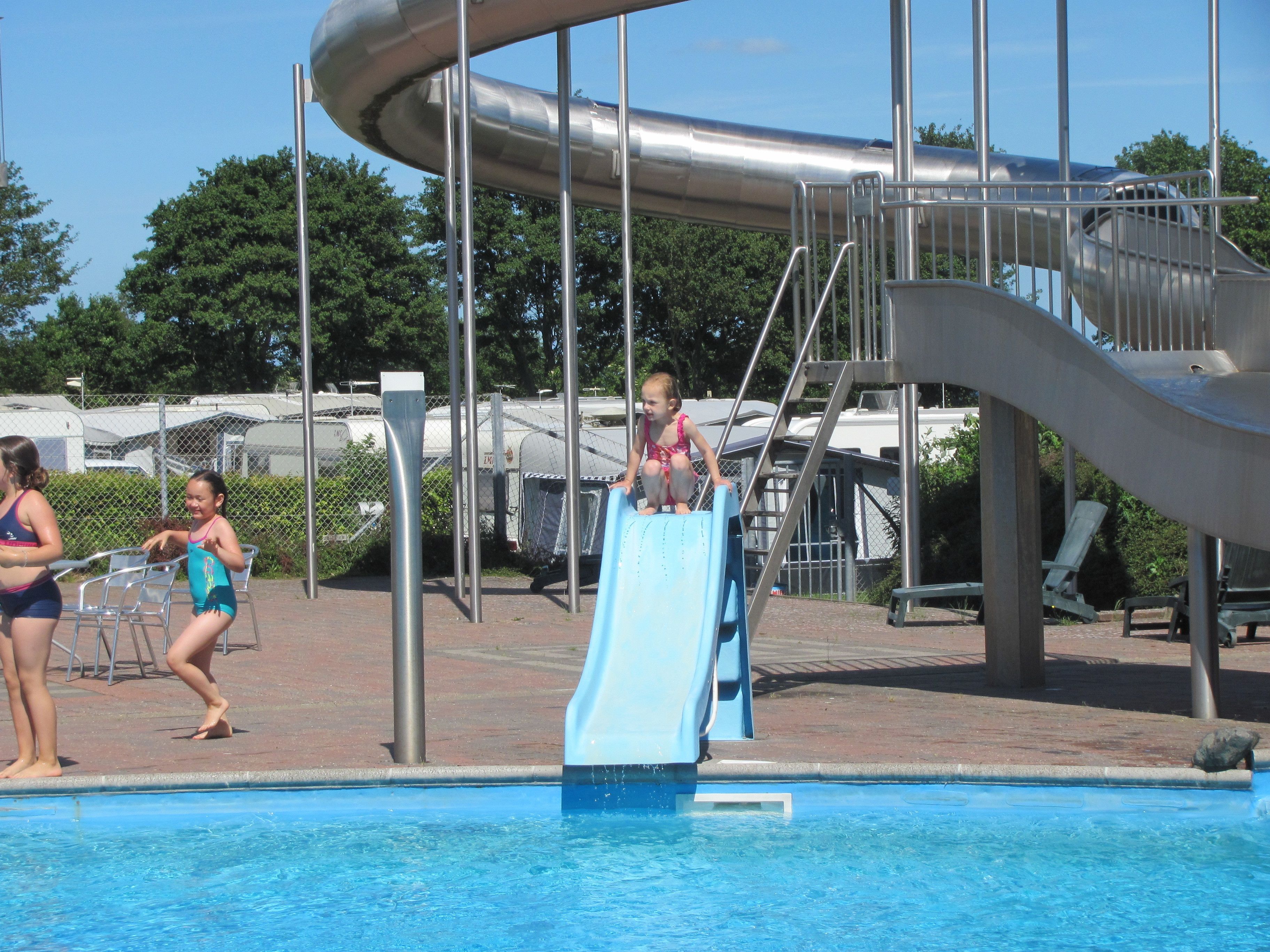 Una piscina con tobogán y estructura metálica.