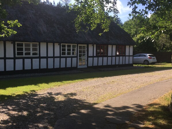 A traditional thatched-roof building with a gravel driveway and a parked car. - Dancamps Trelde Næs (Fredericia)