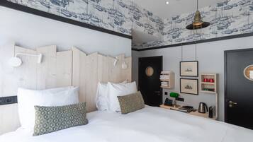 A modern hotel room with a large bed, wooden headboard, and a wall with nautical-themed wallpaper.