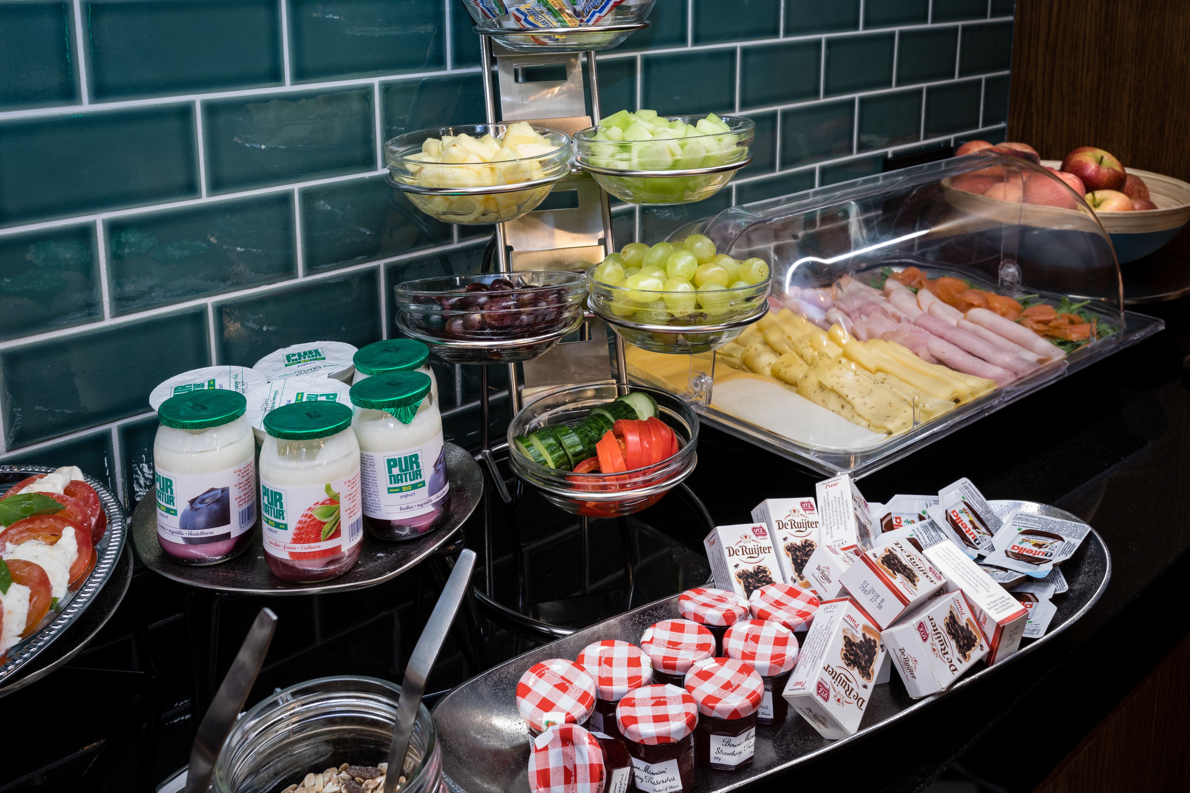 A buffet with various food items including fruits, vegetables, and condiments.