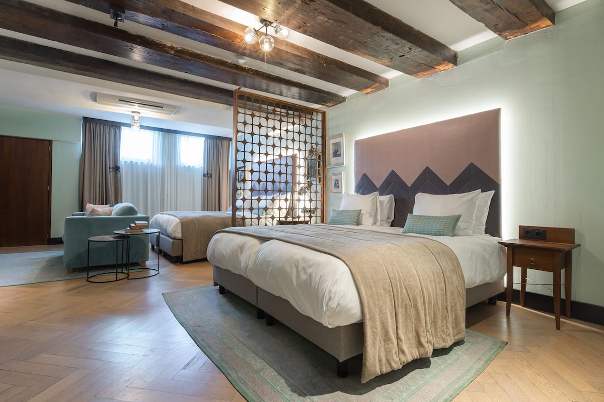 Quarto com uma cama grande, um sofá, uma mesa pequena e um painel decorativo.