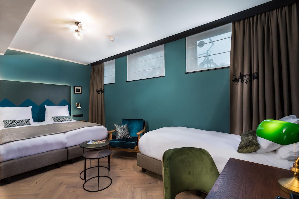 Quarto de hotel com duas camas, uma mesa, uma cadeira e uma pequena mesa.