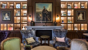 A library with bookshelves, a fireplace, and two armchairs. - The Hendrick's Hotel (Amsterdam)
