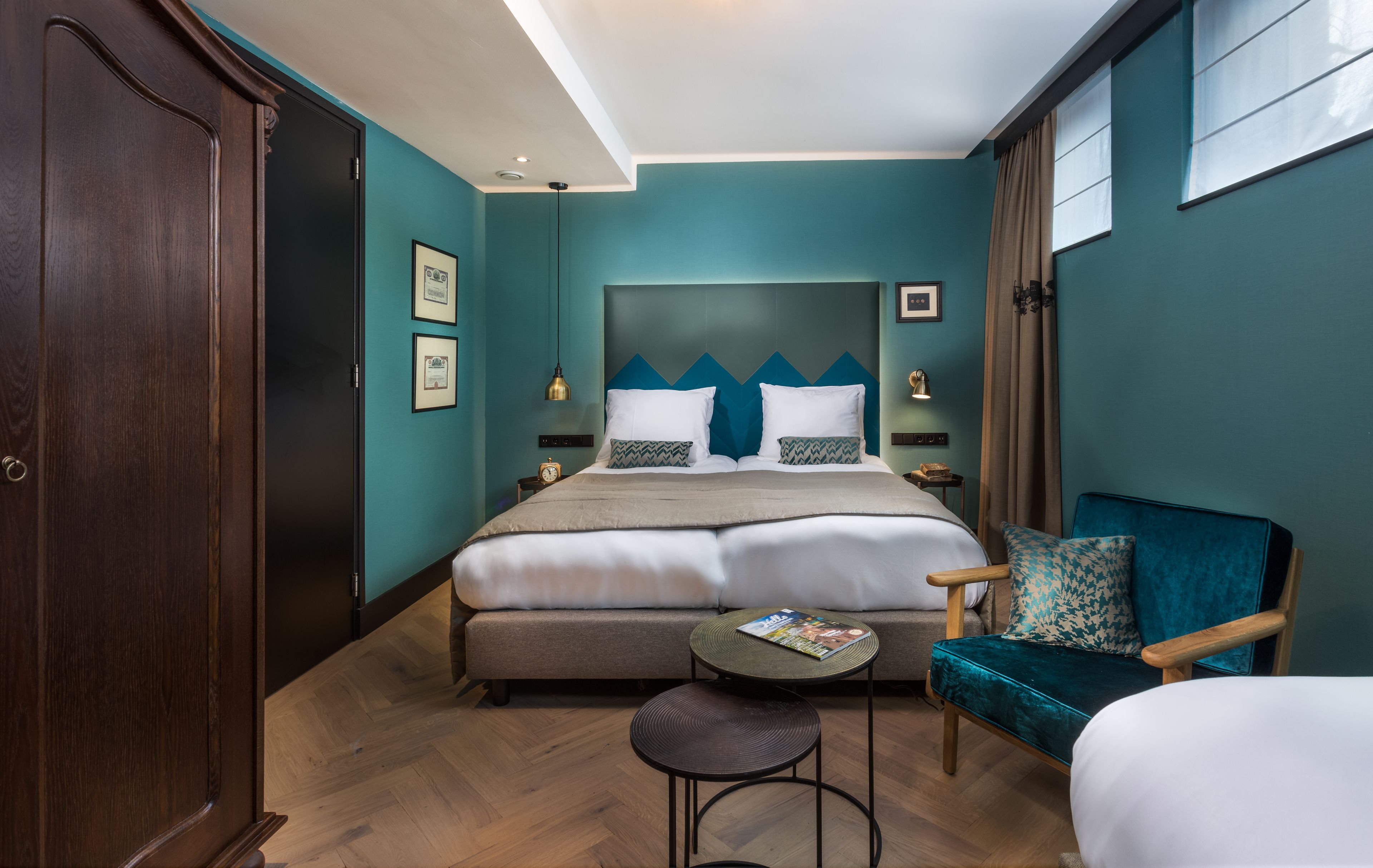 Una habitación de hotel con una cama, una silla, una mesita y un armario.