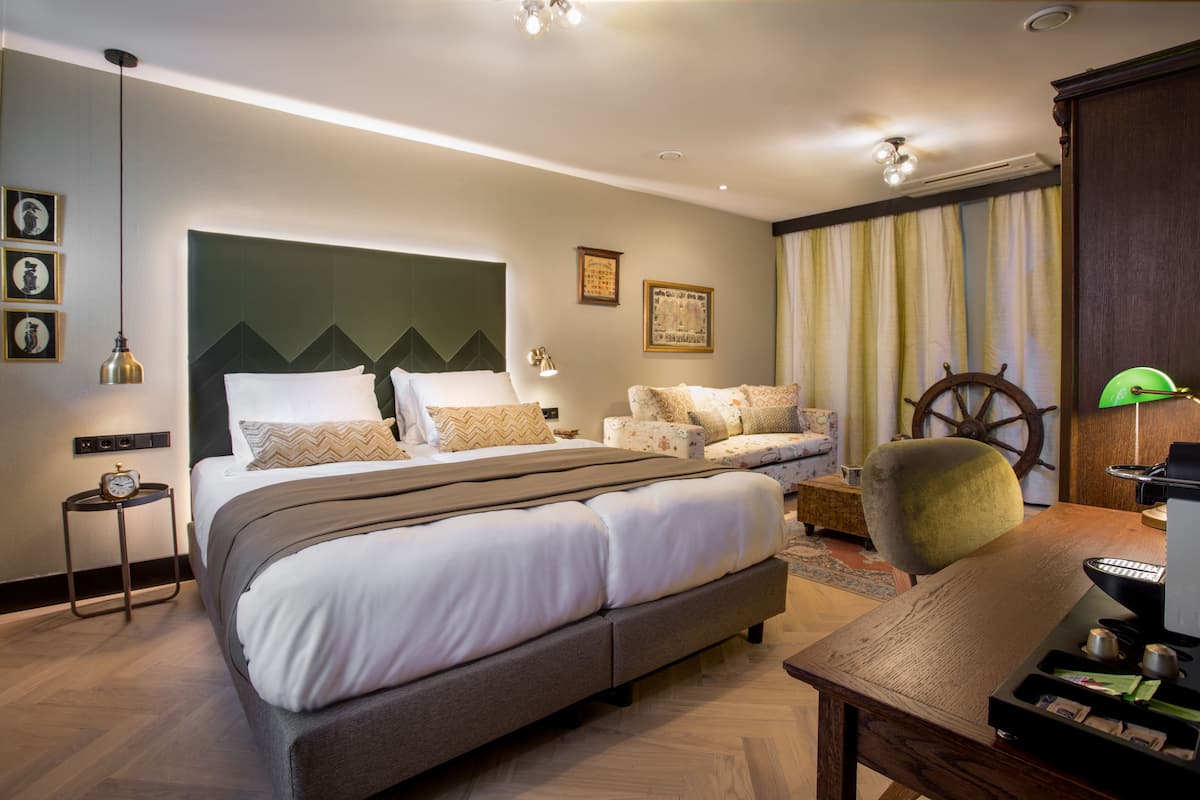 Quarto de hotel moderno com uma cama grande, uma escrivaninha com um computador, uma cadeira e uma decoração com leme de navio.
