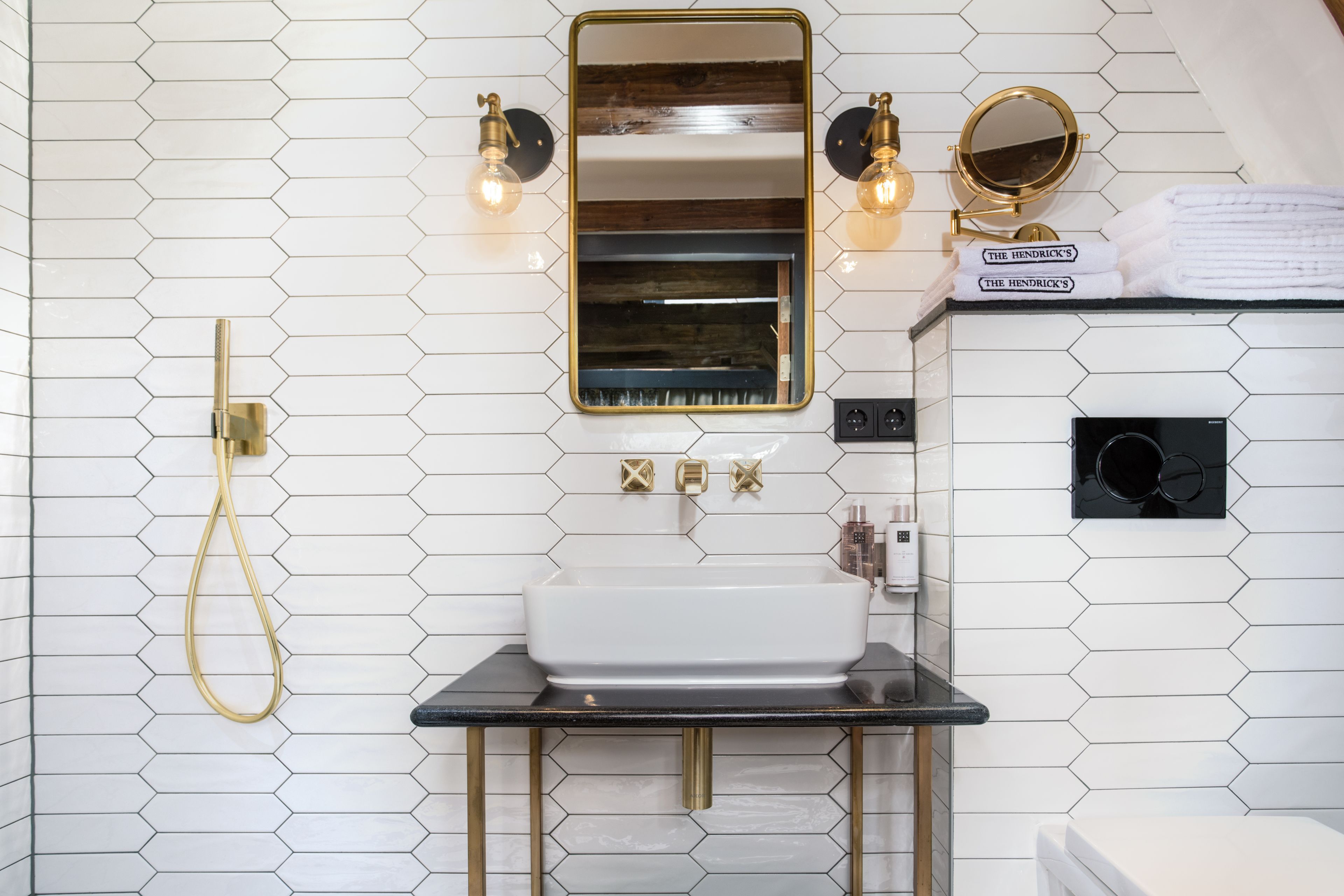 A bathroom with a white sink, gold fixtures, and a mirror above it.