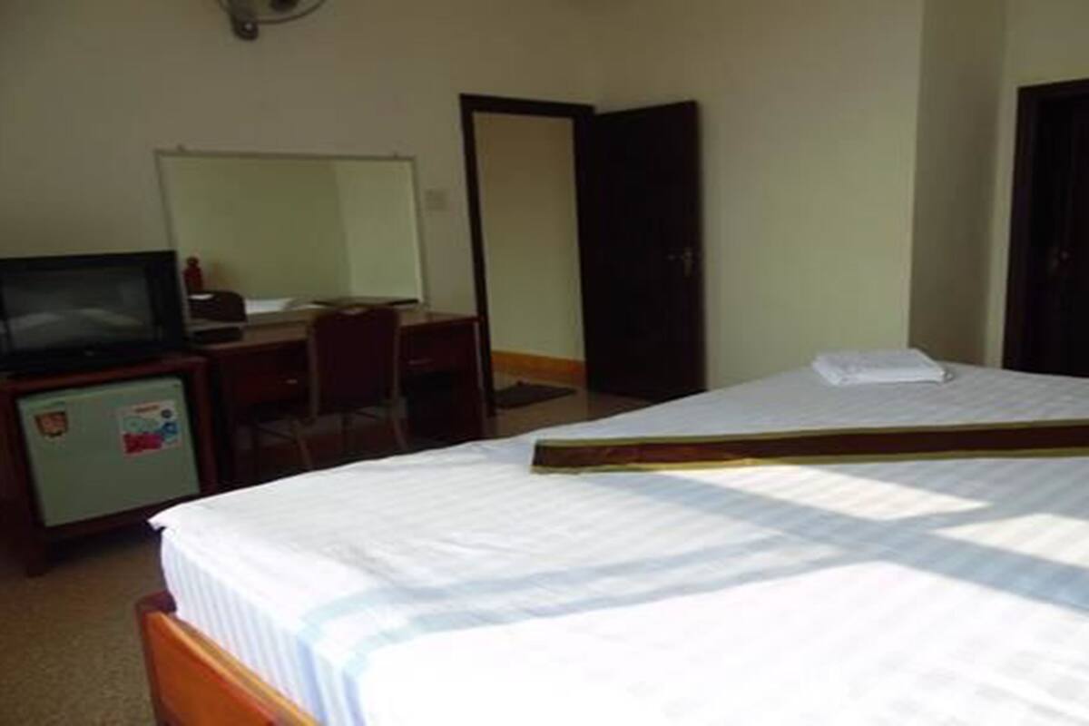 Une chambre d’hôtel équipée d’un lit, d’un bureau, d’une télévision et d’une armoire.