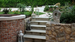 A stone staircase leading to a brick wall with a lantern and a decorative stone piece. - Ca' Muretta Relais (Bardolino)