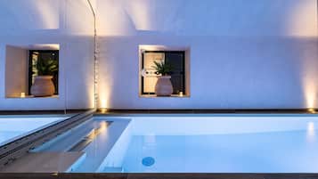 Relax by the sleek pool surrounded by lush greenery and a dark deck.