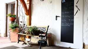 A wooden bench outside a building with a chalkboard menu listing food items and prices. - Bimesmeier Gasthof & Pension (Koesslarn)