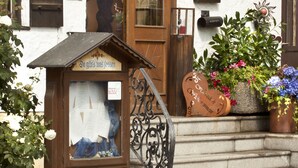 A building with a wooden door, a small shop with a sign, and a staircase leading up to the entrance. - Bimesmeier Gasthof & Pension (Koesslarn)