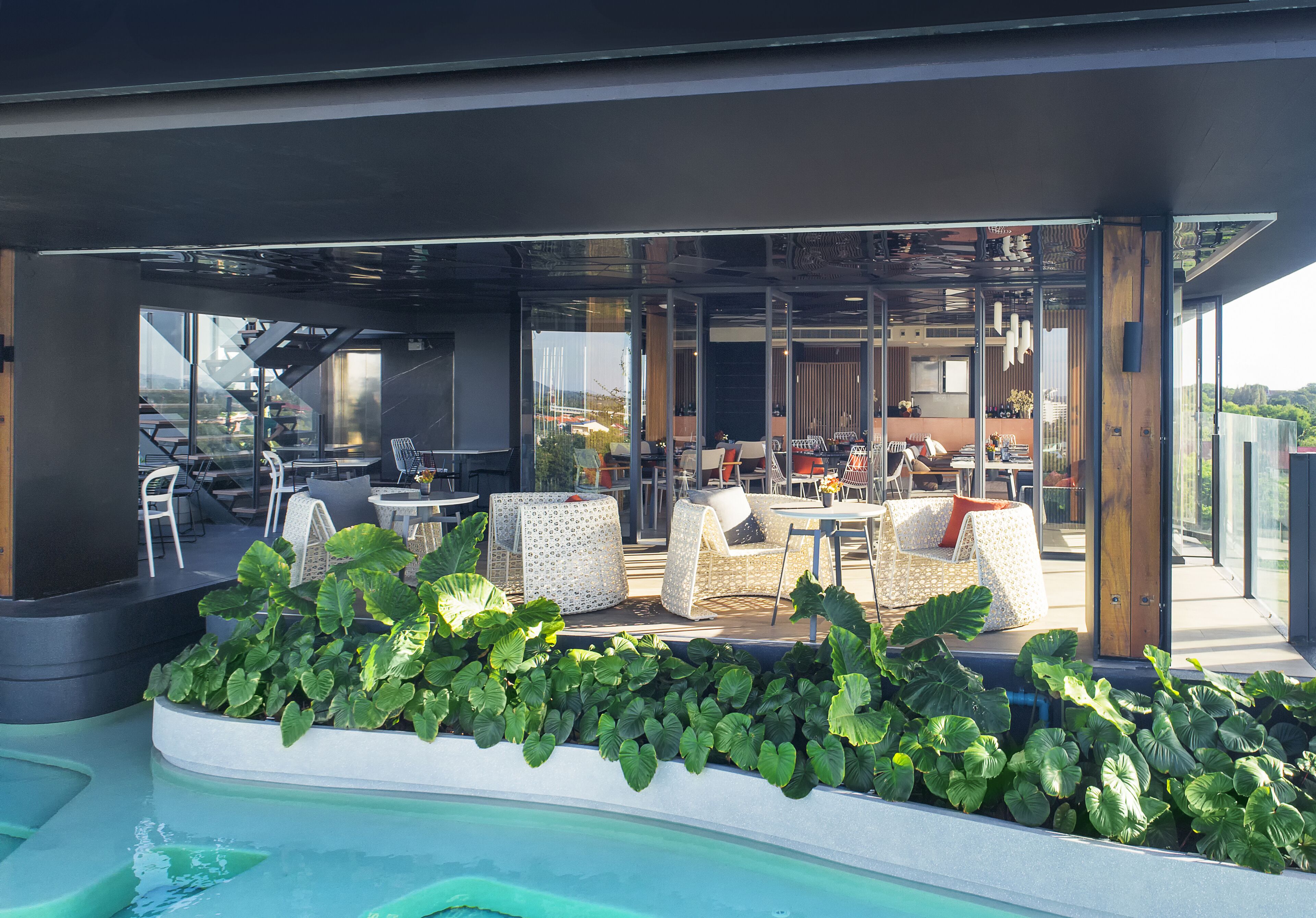 A modern outdoor seating area with a pool, featuring lounge chairs and tables.
