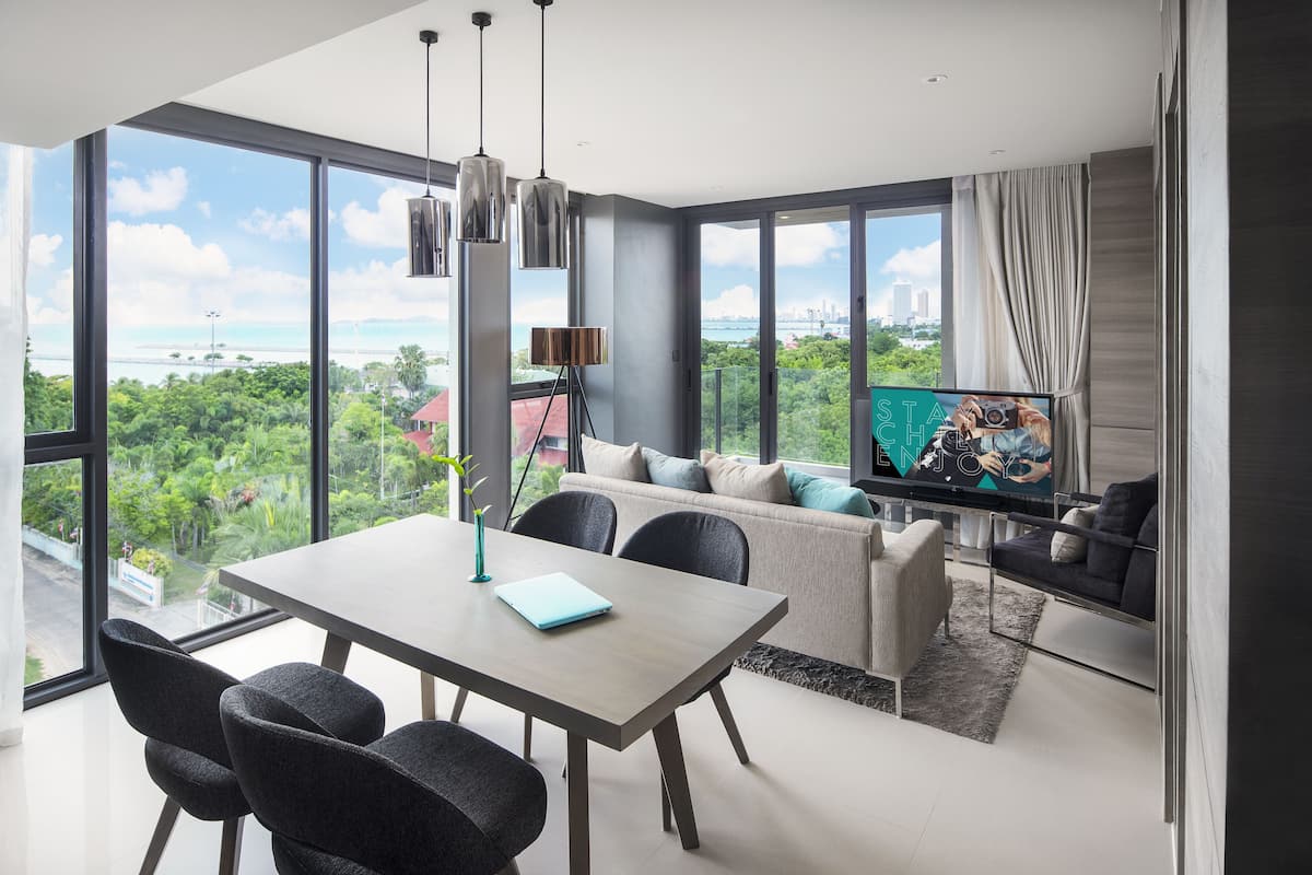 A modern living room with a large window, a dining table, and a sofa.