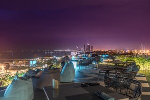 A rooftop bar with seating and a view of the city skyline at night. - Seaphere Pattaya Hotel (Sattahip)