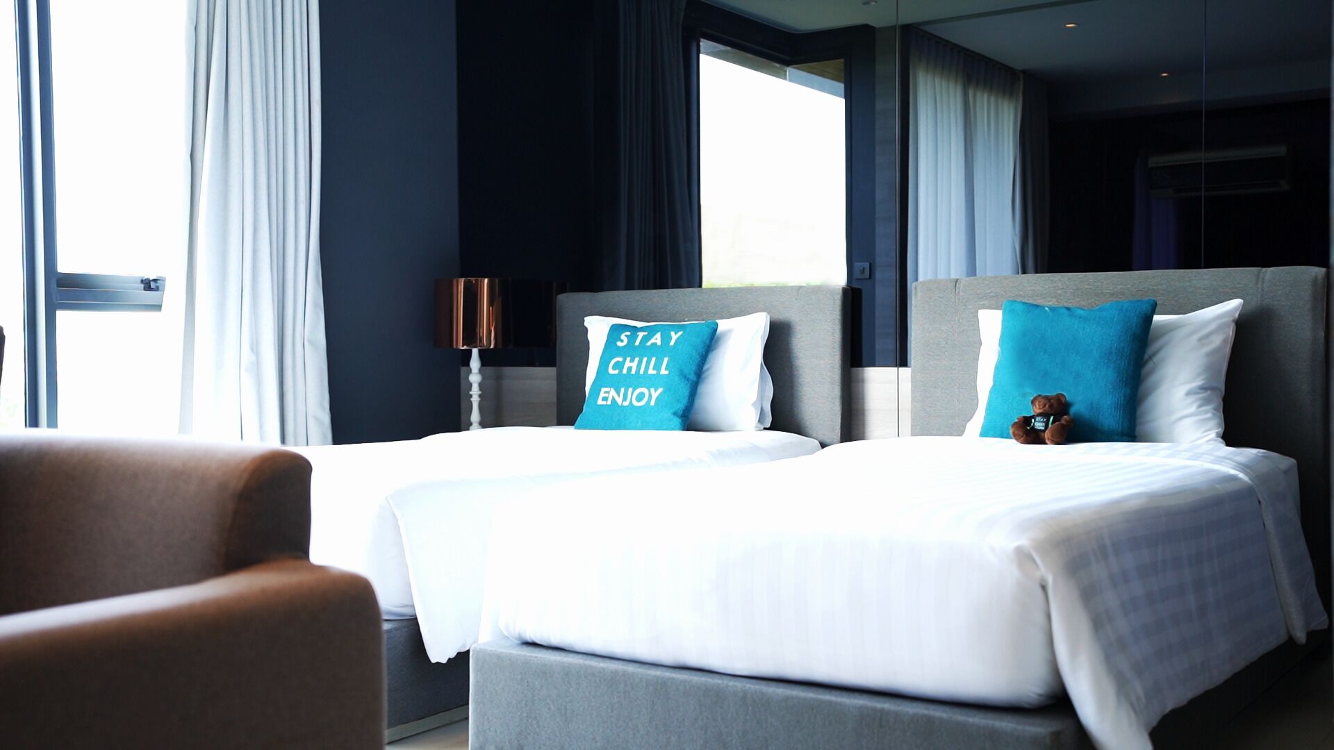 A hotel room with two beds, a sofa, and a lamp.