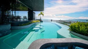Une piscine à l’eau d’un bleu cristallin, entourée de chaises longues et offrant une vue sur l’océan.