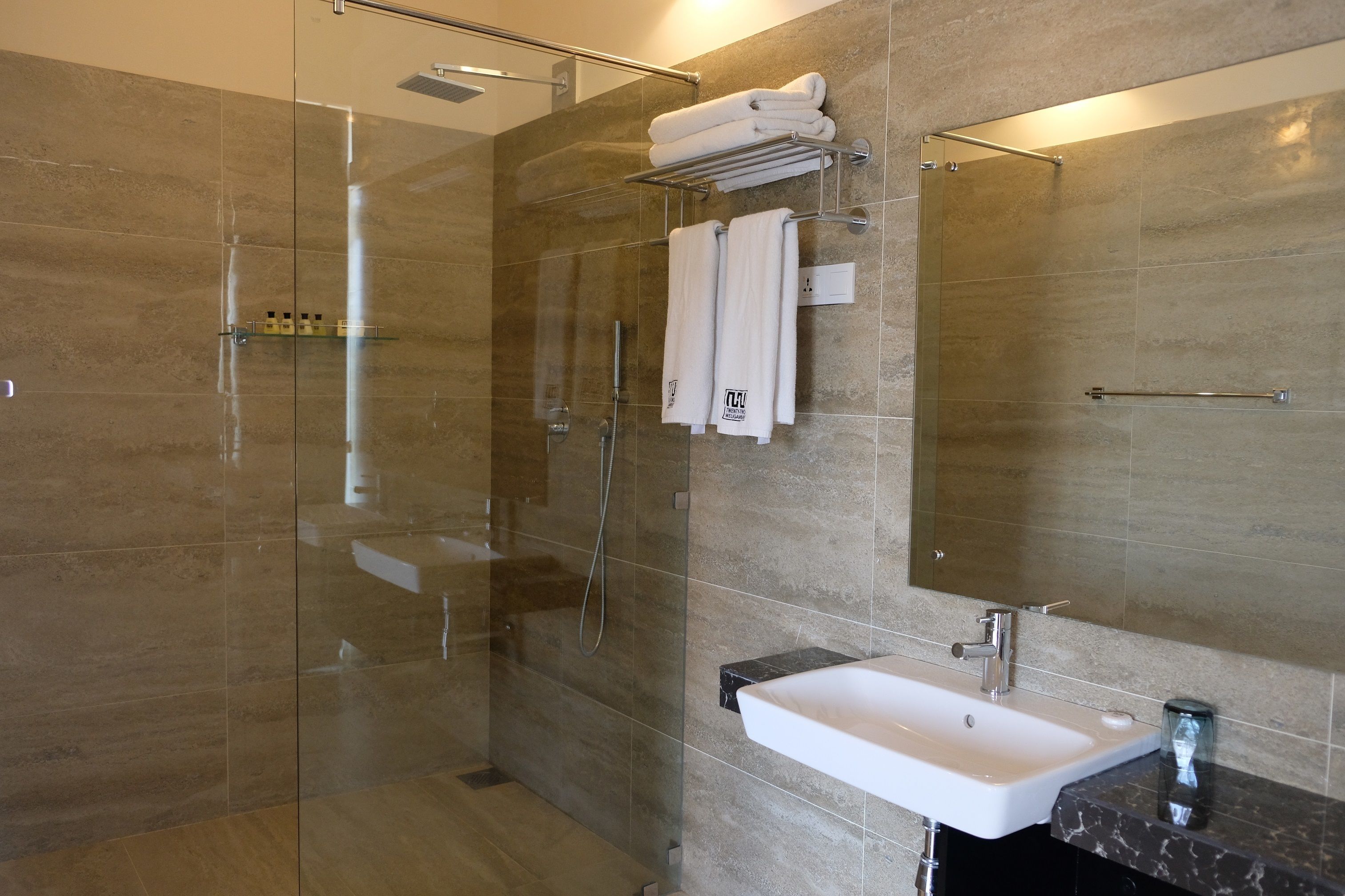 A modern bathroom with a glass-enclosed shower, a white sink, and a marble countertop.