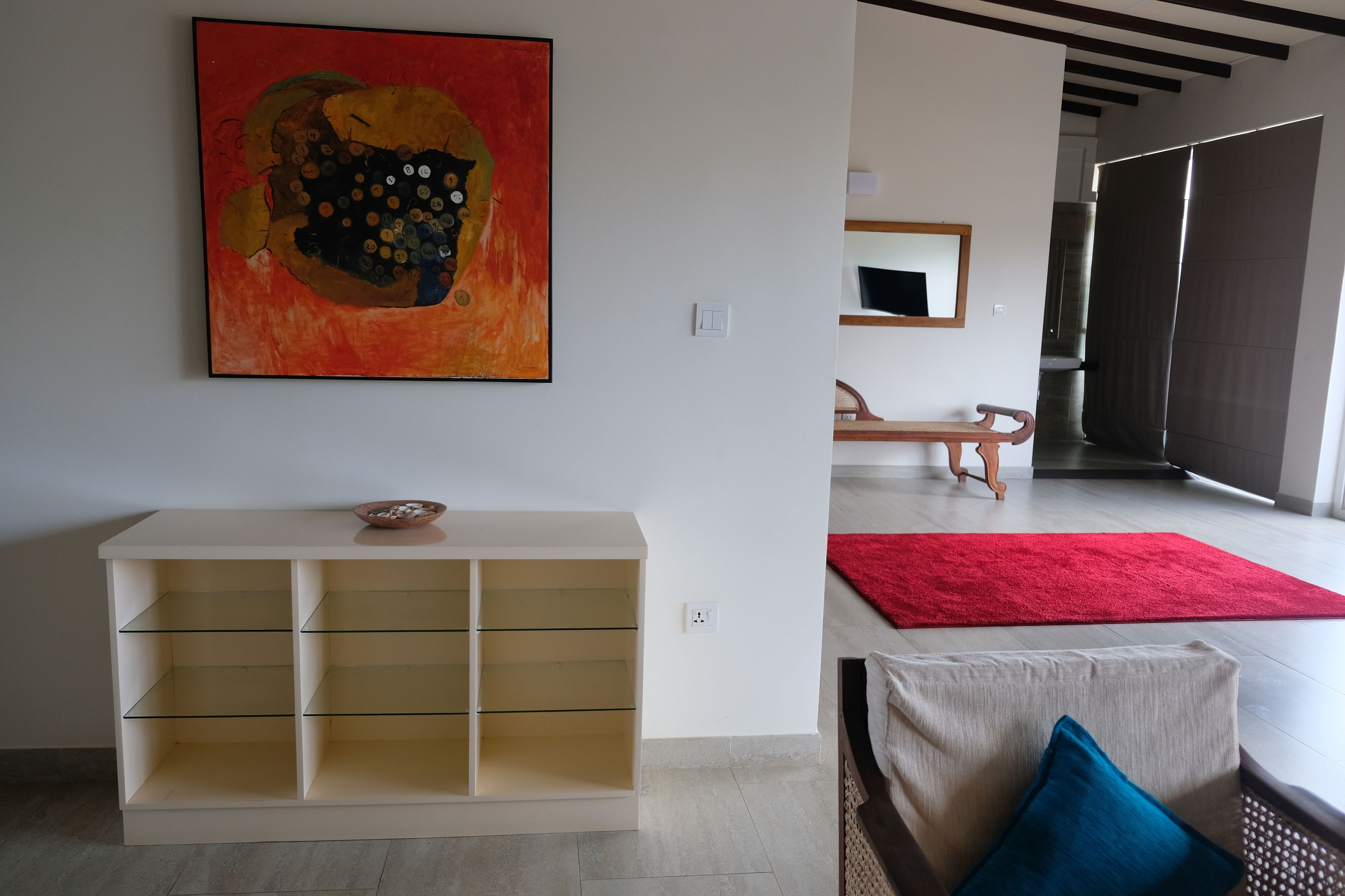 Ein modernes Wohnzimmer mit einem weißen Konsolentisch, einem roten Teppich und einem großen abstrakten Gemälde an der Wand.