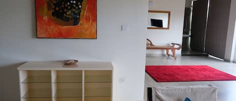 Ein modernes Wohnzimmer mit einem weißen Konsolentisch, einem roten Teppich und einem großen abstrakten Gemälde an der Wand.