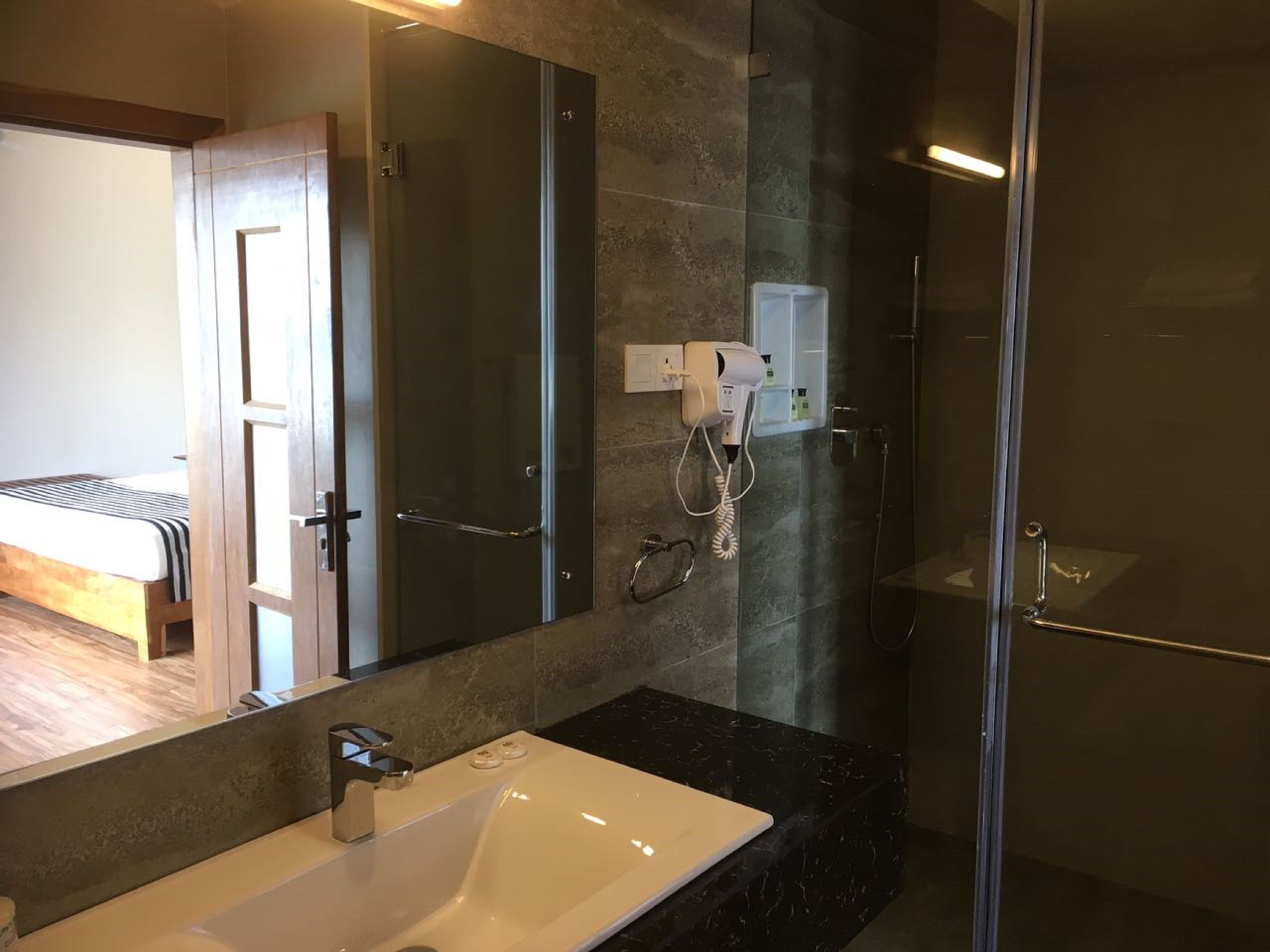 Un baño moderno con cabina de ducha de vidrio, un espejo grande y un lavabo con encimera de mármol.