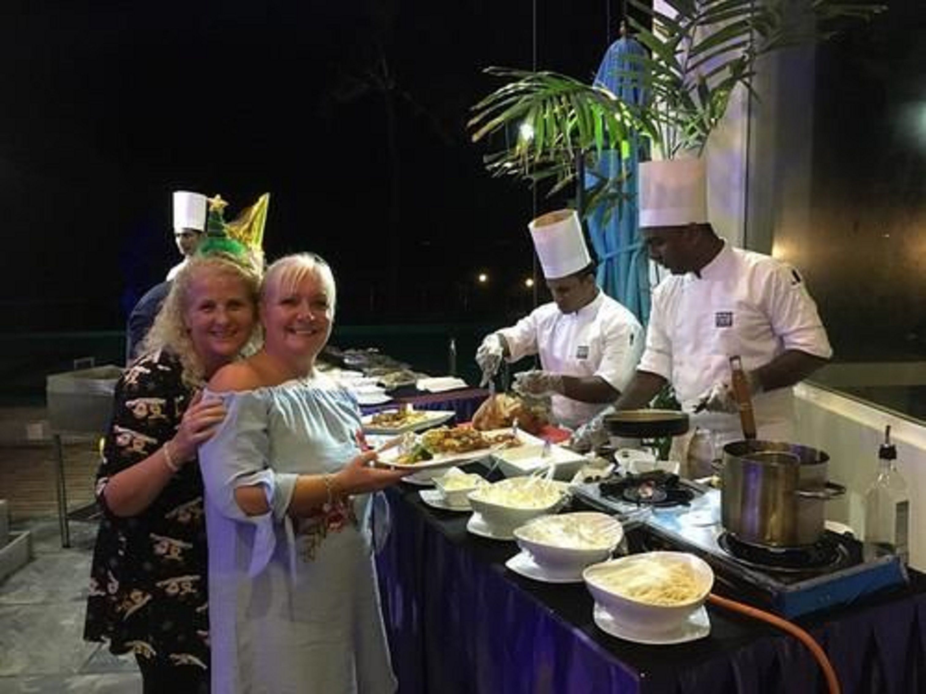 Una mesa de buffet con diversos platos y un cocinero preparando comida.