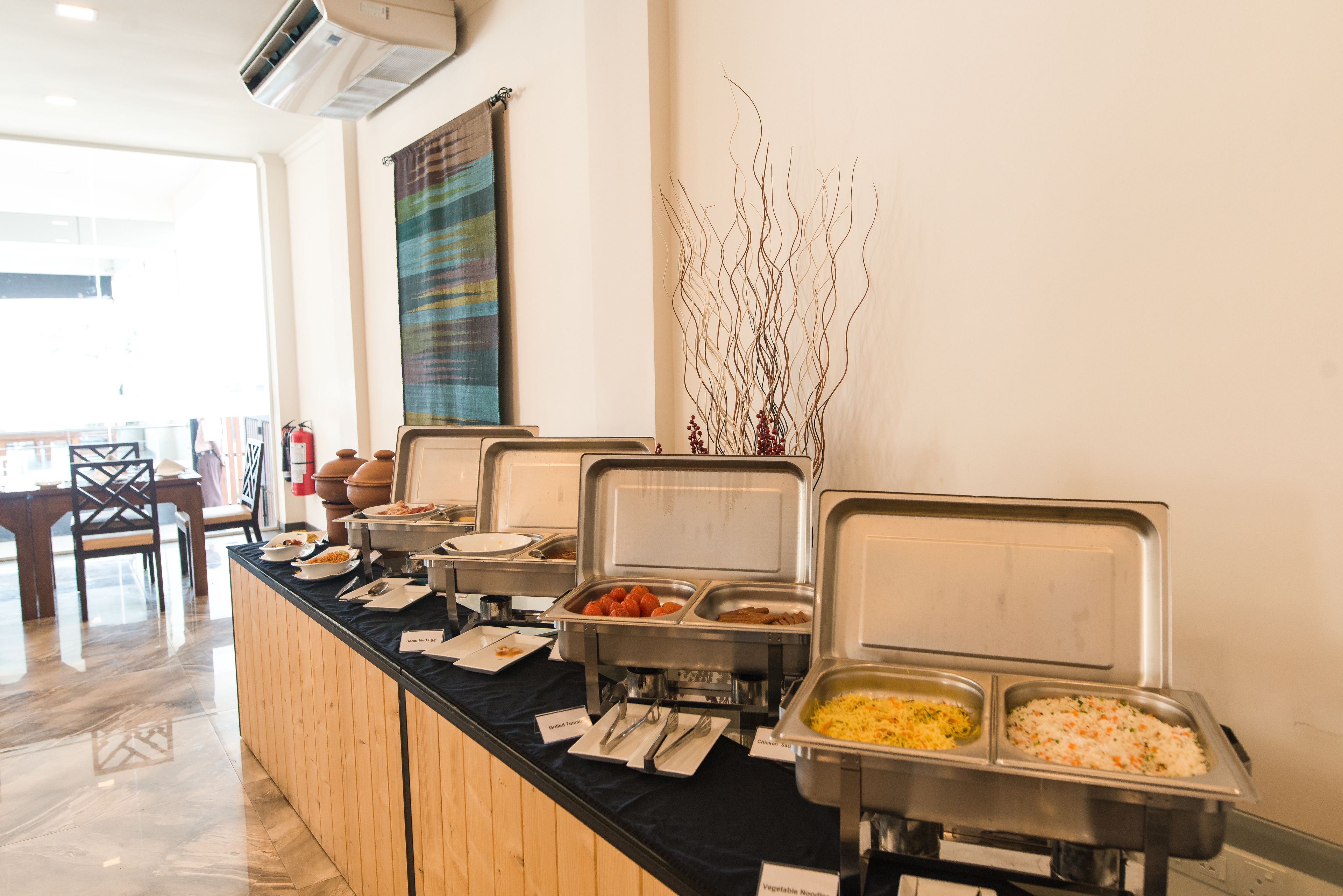 A buffet setup with various food options, including a section for vegetable noodles, arranged on a counter with a black tablecloth.