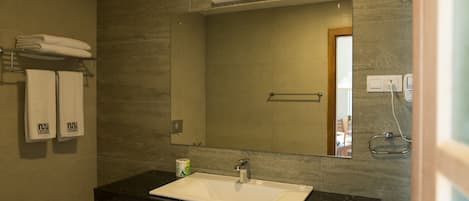 A bathroom with a white sink, dark marble countertop, and a large mirror.