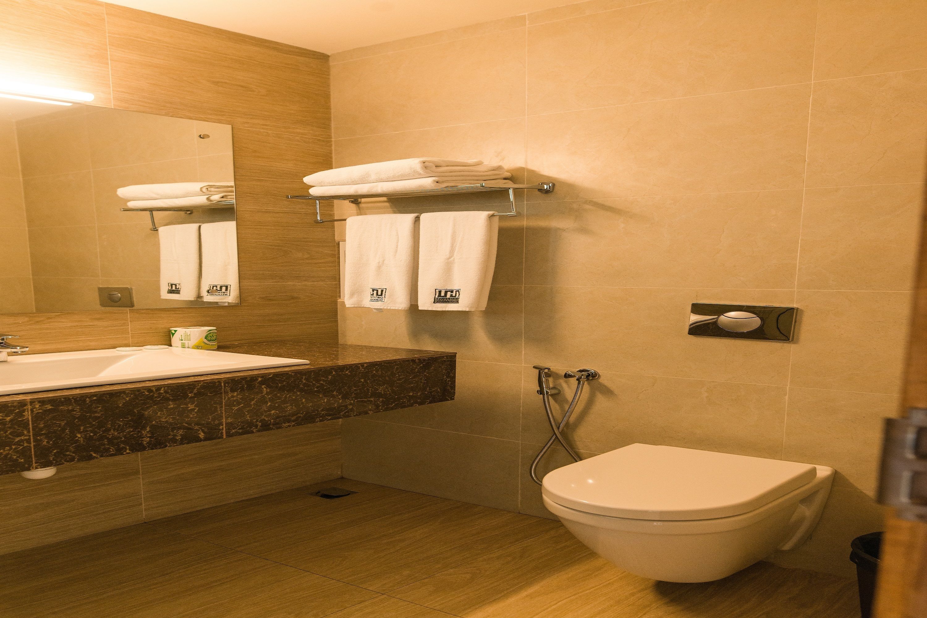A modern bathroom with a sink, mirror, towel rack, toilet, and shower.