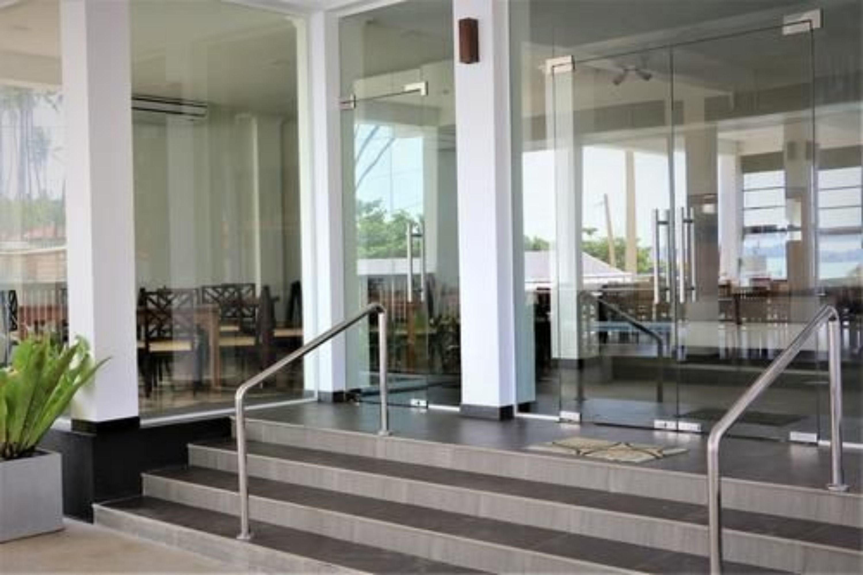 Un vestíbulo moderno de hotel con puertas de vidrio, una escalera y una zona de estar con sillones.