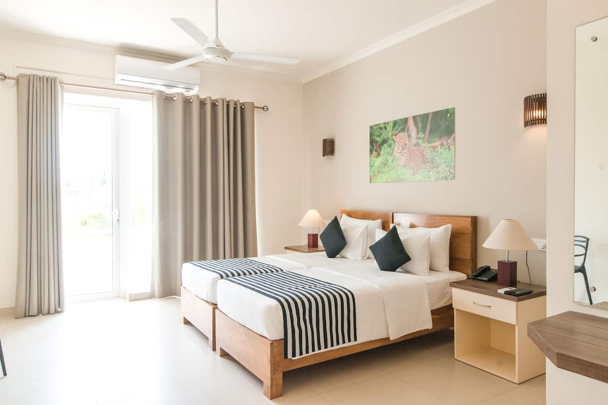 A hotel room with a bed, bedside tables, a desk, and a ceiling fan.