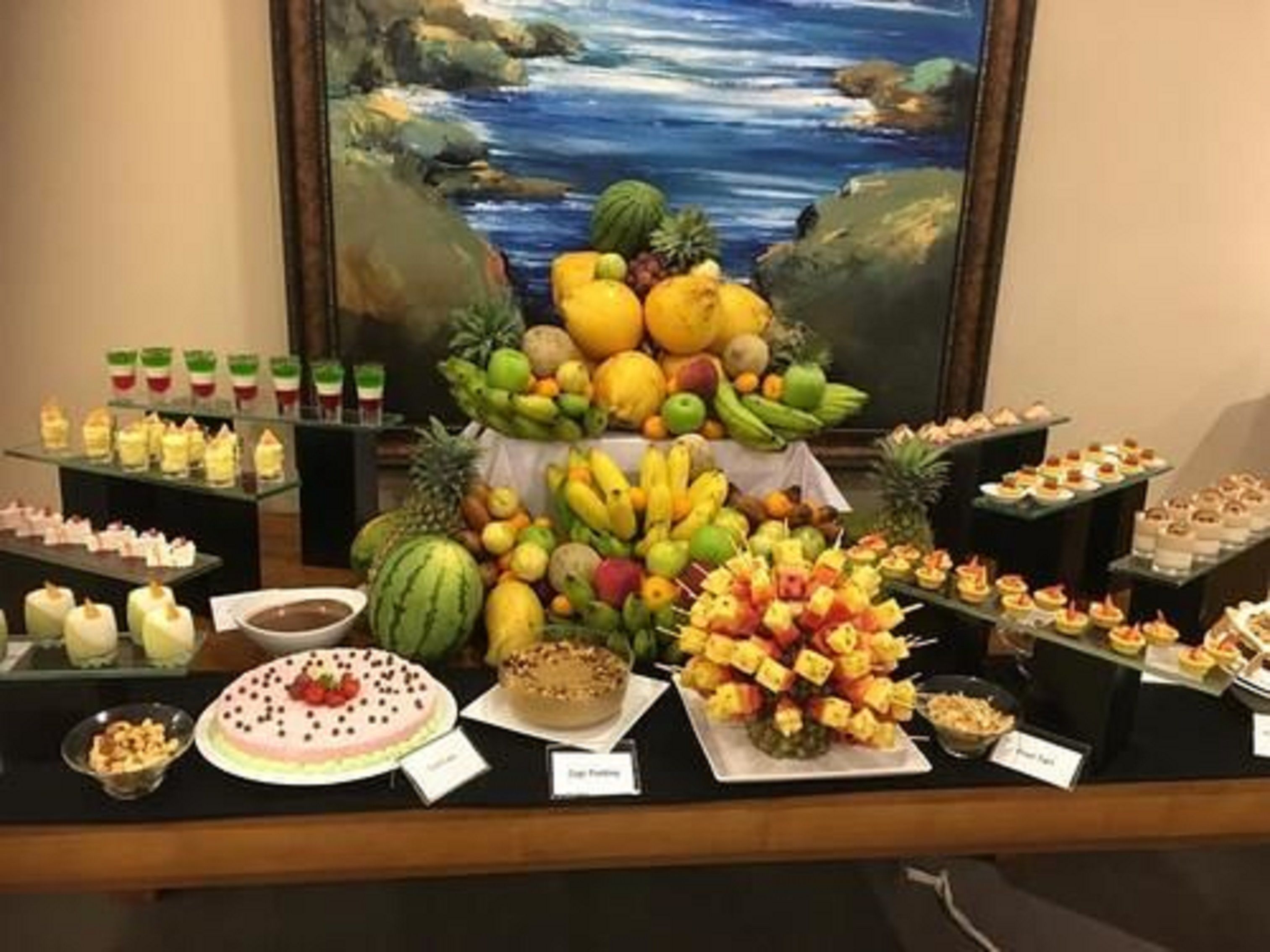 A buffet table with various fruits, desserts, and appetizers.