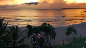 A beach scene with a sunset, palm trees, and a small structure with colorful umbrellas. - Twenty-Two Weligambay (Weligama)