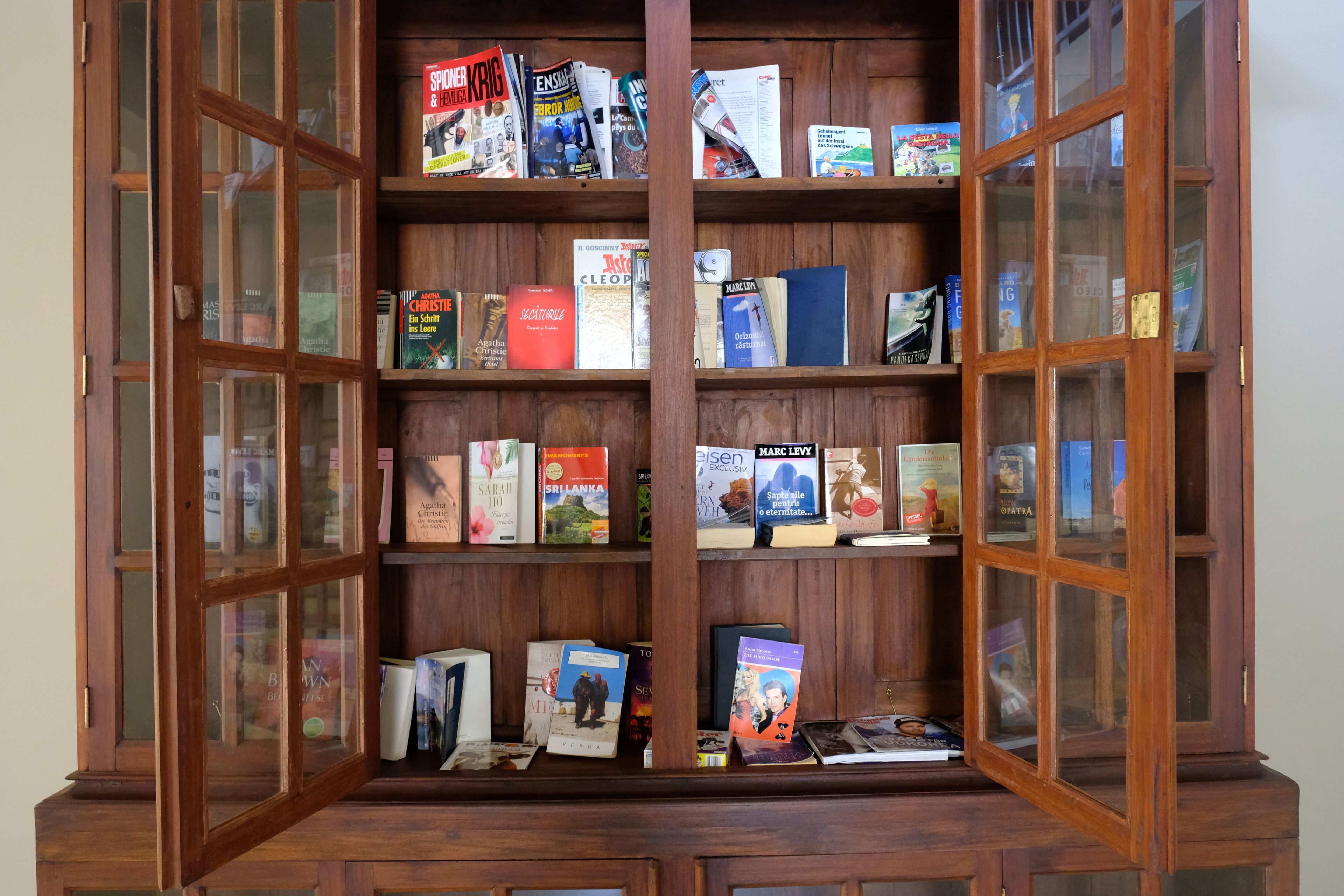 A wooden bookcase with multiple shelves filled with books.