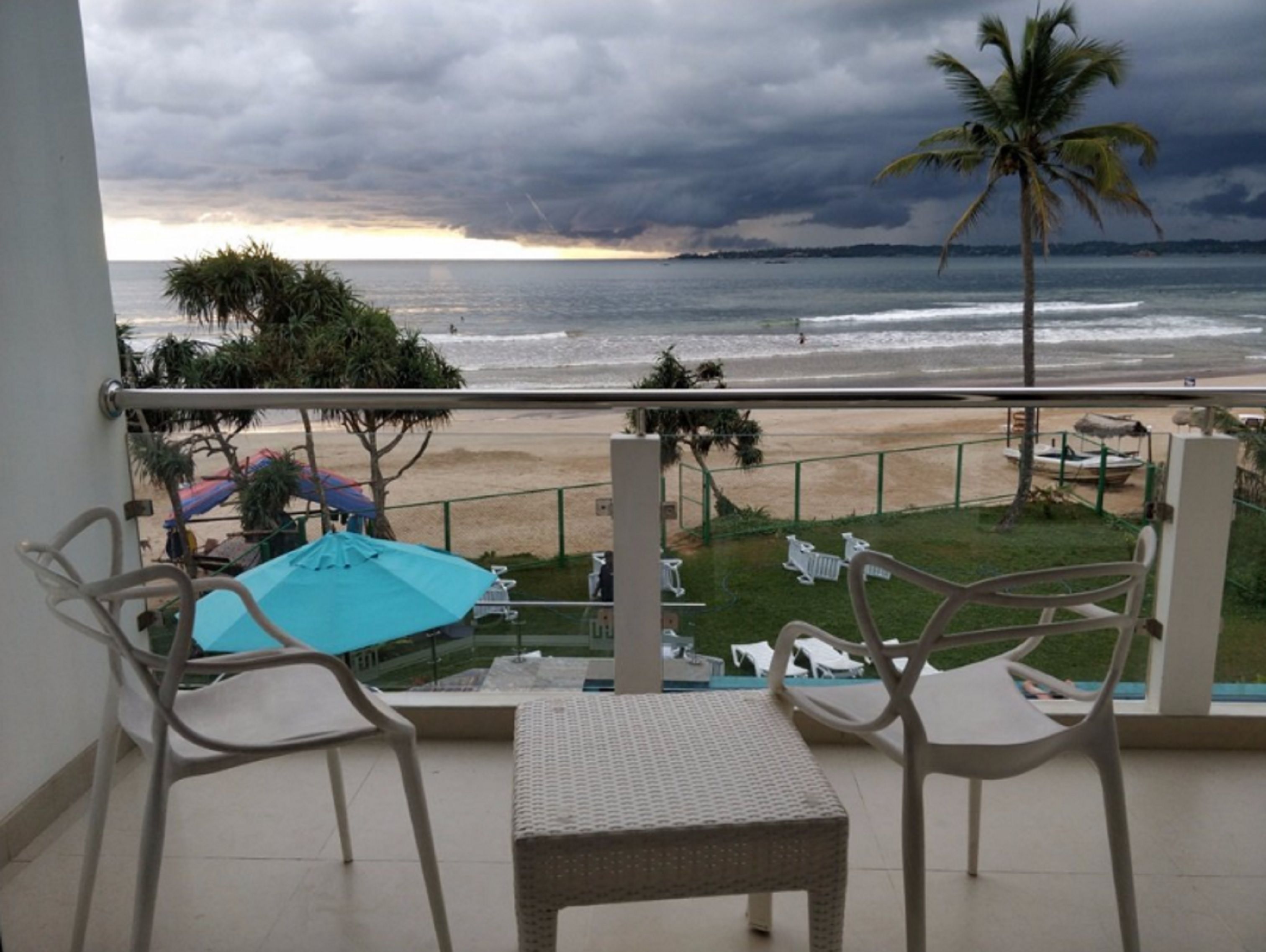 Un balcone con vista sulla spiaggia e sull'oceano. Sono presenti due sedie e un tavolino.