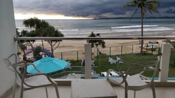Un balcone con vista sulla spiaggia e sull'oceano. Sono presenti due sedie e un tavolino.