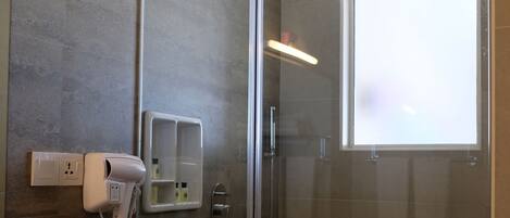 A modern bathroom with a glass shower enclosure, a hairdryer, and a towel rack.