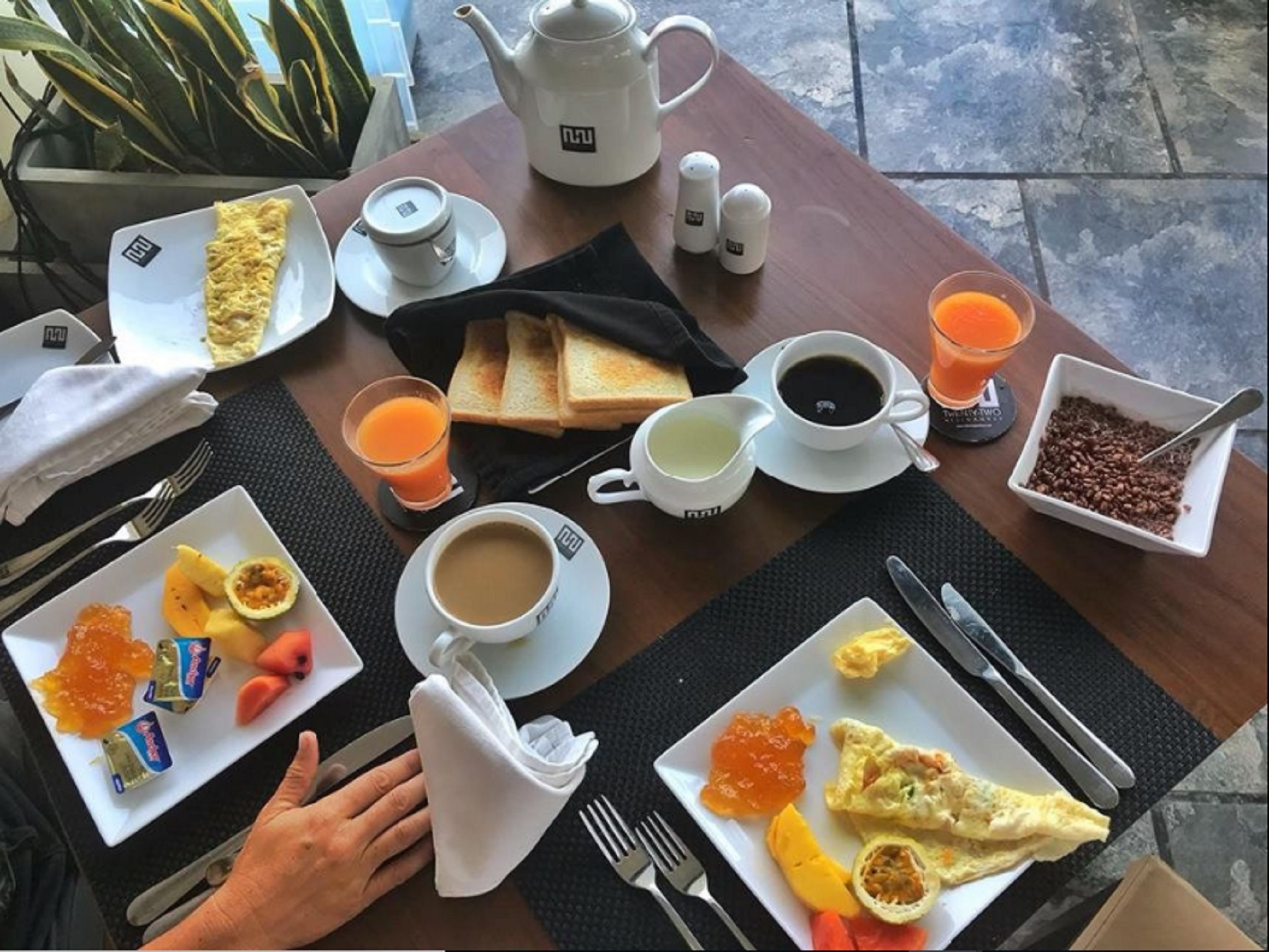 A breakfast table with various food items, a teapot, cups, and a tray.