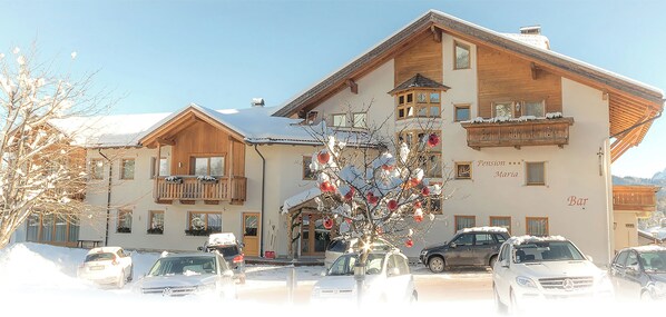 A hotel with a traditional Alpine architectural style, featuring wooden balconies and a snow-covered roof. - Pension Maria (San Martino in Badia)