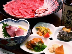 Une table où l’on trouve divers plats, notamment de la viande crue, un bol de soupe et d’autres aliments.