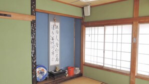 Una habitación japonesa tradicional con suelo de tatami, puertas correderas shoji y un pergamino colgado con caligrafía.