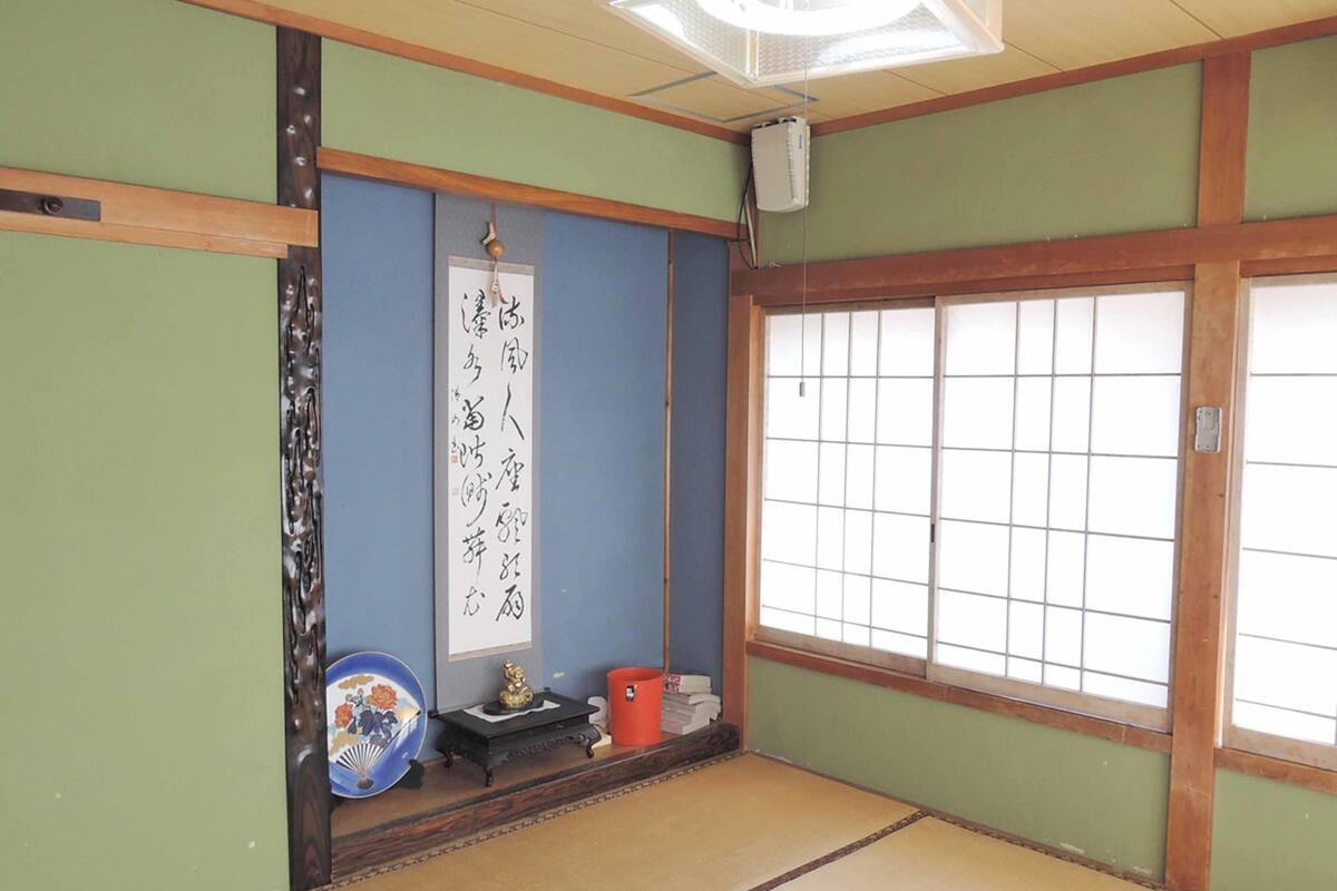 A traditional Japanese room with tatami flooring, a shoji screen door, and a hanging scroll with calligraphy.