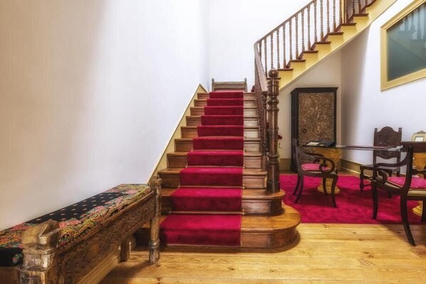 A staircase with red carpet, wooden railings, and a bench at the bottom. - A Vianesa Guest House (Viana do Castelo)