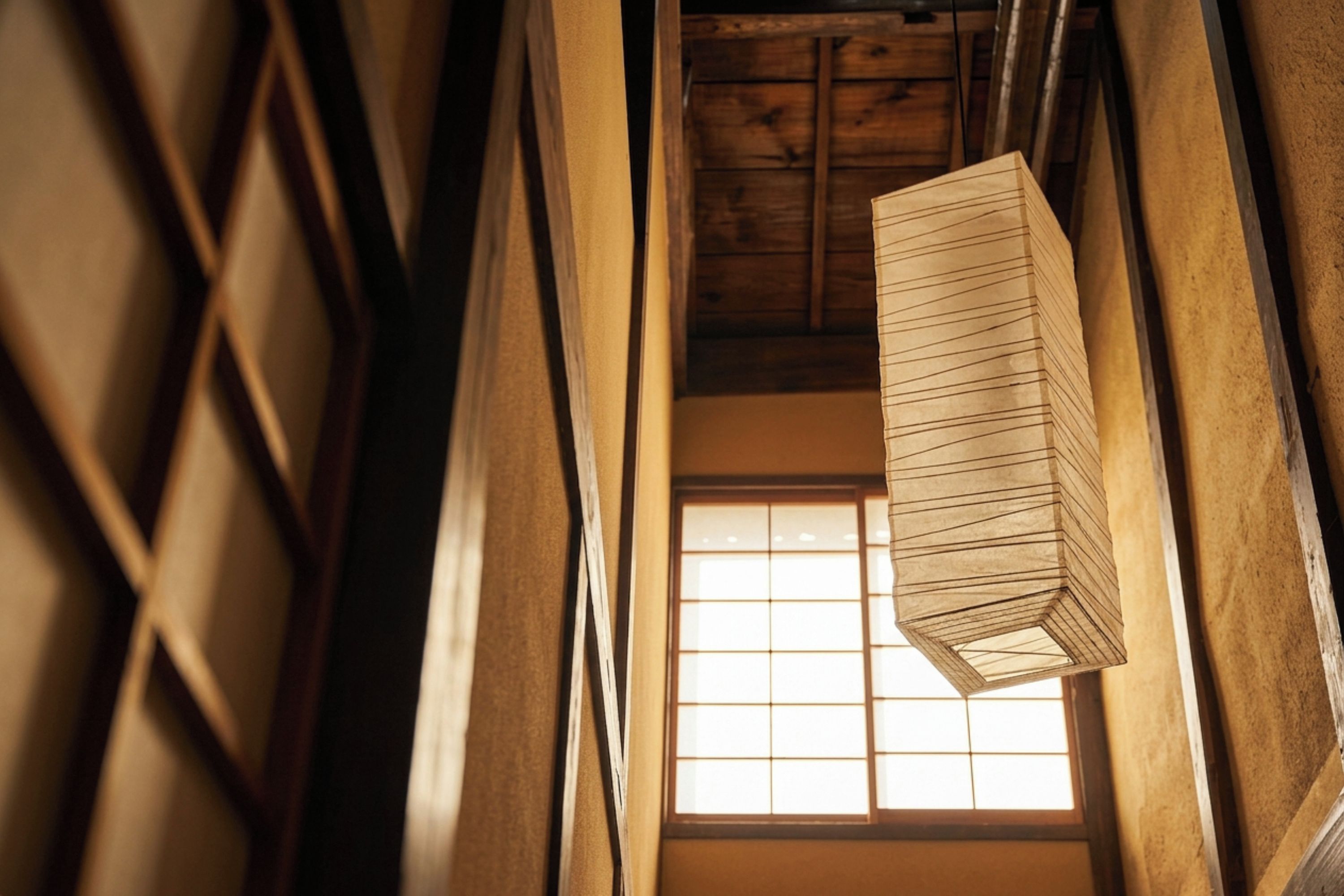 A narrow corridor with wooden walls and a hanging lantern.